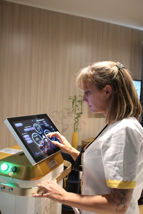 Femme en uniforme utilisant un écran tactile pour contrôler un appareil médical.