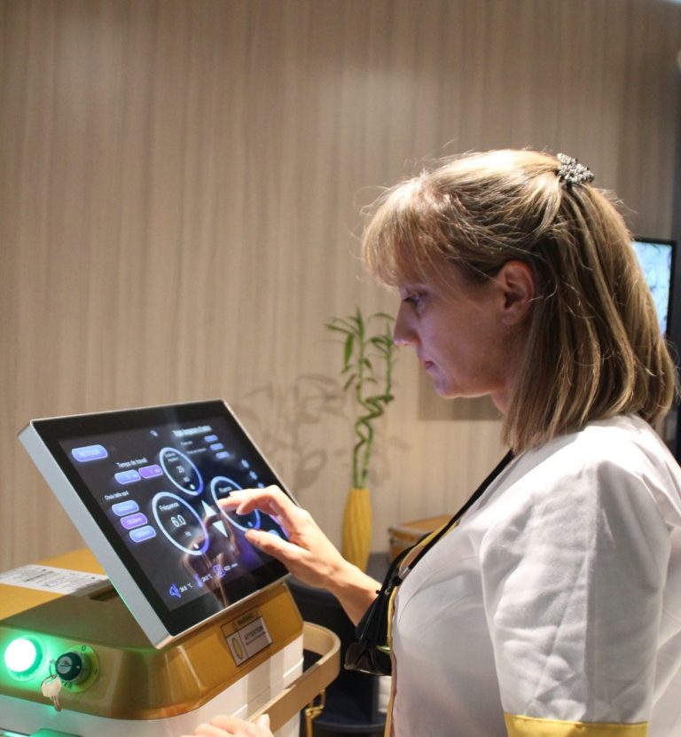 Silféa épilation Stéphanie, infirmière, en blouse blanche utilisant un écran tactile dans un environnement médical : réglage de l'appareil épilation laser.